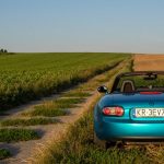 Convertible Mazda MX-5 on a picturesque rural road in Poland's countryside.